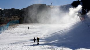Una de les pistes d'esquí de La Molina (Cerdanya), amb els canons produint neu i algunes persones passejant-hi