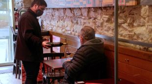 Un cambrer servint a un client en un bar de Girona