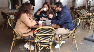 Tres persones esmorzant en una terrassa de la plaça de la Independència de Girona