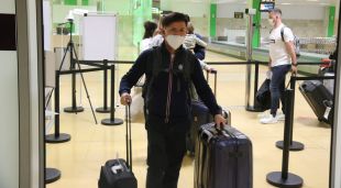 Un jove arribant per la porta i la cua de gent a l'aeroport de Girona Costa Brava