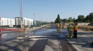 Efectius de serveis d'emergències davant d'una taca de gasoil vessat per un camió accidentat