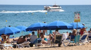 Un grup de turistes amb tumbones a la platja a Lloret de Mar