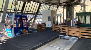 Vista de l'ascensor, al fons, amb una cabina del telefèric en primer terme