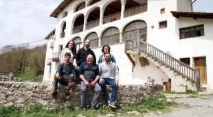 Els usuaris, el masover i els impulsors de Fem Coliving a Sant Joan de les Abadesses (Ripollès) amb el mas de fons