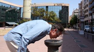 Un home bebent de la font instal·lada a la plaça de Miquel Santaló