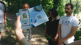 Un mòbil amb el projecte Vorater en pantalla i participants en un exercici de relaxació