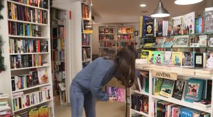 La propietària d'una llibreria de Calonge col·loca els llibres al prestatge