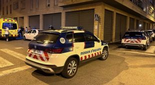 Cotxes patrulla dels Mossos d'Esquadra i una ambulància del SEM a l'entorn d'un edifici en un dels pisos del qual s'ha trobat una dona morta