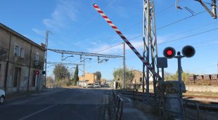Les barreres del pas a nivell de Flaçà abaixant-se abans del pas del tren