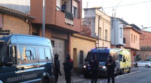 Un home mira pel balcó minuts abans de ser desnonat del pis mentre els Mossos d'Esquadra vigilen al carrer