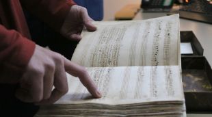 Imatge del cançoner a mans de la Judit Badia, directora de la biblioteca d'Olot