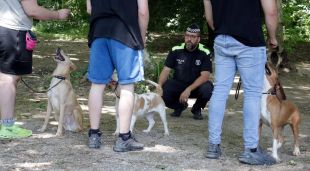 Els tres joves fent obeir els gossos amb la guia de l'agent de la Policia Municipal de Girona