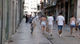 Una bici esquiva vianants passant per la vorera al carrer Nou de Girona