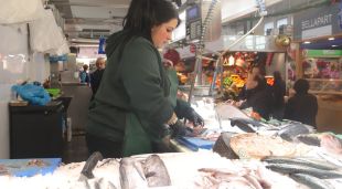 Una peixatera del mercat del Lleó de Girona netejant un peix