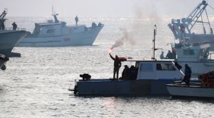 Un pescador amb una bangala encesa en una de les barques a Blanes