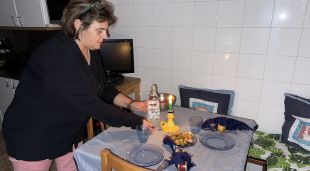 Una dona encén una espelma a la cuina de casa per la manca de llum a l'hora de sopar