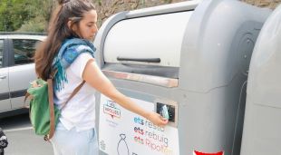 Una veïna de Ribes de Freser posant la targeta electrònica al contenidor