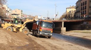 Una màquina aboca sorra acumulada a la llera del riu Onyar a sota de la plaça de Catalunya en un camió