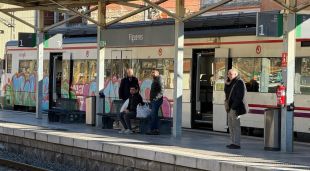Un tren aturat a l'andana amb passatgers esperant a Figueres