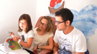 Una família en una de les habitacions decorades amb els murals © ACN