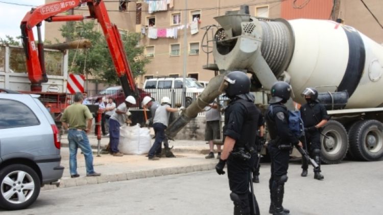 Els Mossos d'Esquadra i els operaris que han tapat el forat del terra des d'on els veïns havien punxat la llum © ACN