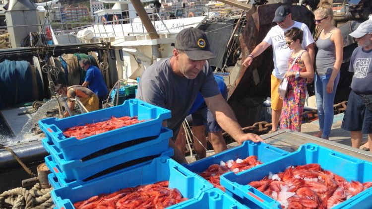 Un pescador de Blanes amb turistes en segon pla observant les captures