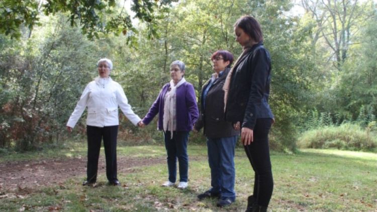 Tres usuàries i una infermera fan exercicis de relaxació al bosc de Can Serra d'Olot © ACN