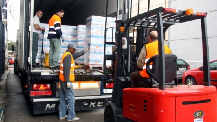 El personal del Banc dels Aliments de Girona descarrega els 12.000 litres de llet © ACN