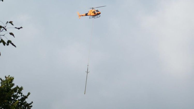 L'helicòpter transportant un dels pals del tram de línia elèctrica renovada a la Garrotxa