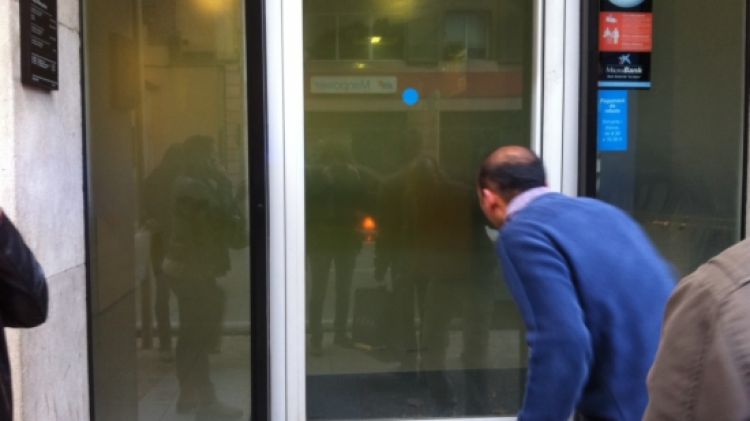 Un vianant intentant veure si hi ha algú a l'interior del caixer © ACN