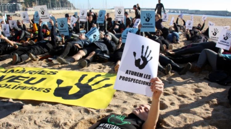 Activistes i nedadors, vestit de negre, s'han estès a la sorra de la platja de Blanes © ACN