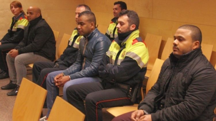 Els tres acusats, emmanillats i custodiats pels mossos, al banc dels acusats © ACN