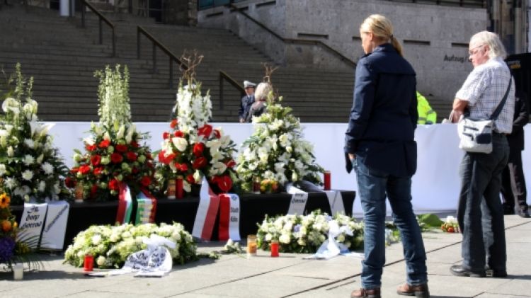 Dues persones miren les ofrenes florals a les víctimes del vol de Germanwings davant de la catedral de Colònia © ACN