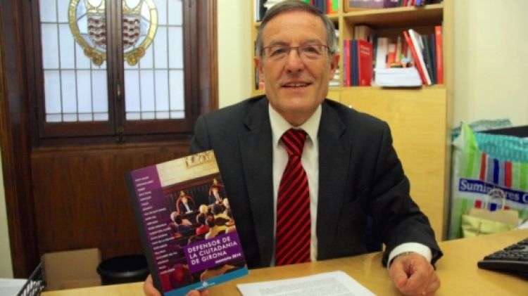 El defensor de la ciutadania de Girona, Ramon Llorente, al seu despatx amb la memòria del 2014 © ACN