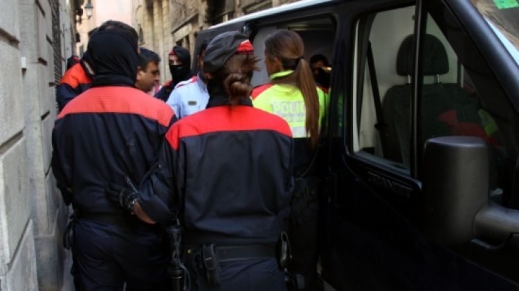 Un grup d'agents dels Mossos d'Esquadra al costat d'un dels detinguts al carrer Regomir de Barcelona © ACN