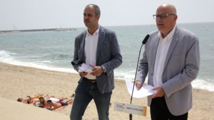 Un grup de banyistes observa des de la sorra la roda de premsa de Miquel Buch i Lluis Corominas © ACN