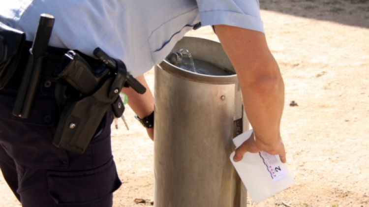 Un agents dels Mossos pren mostres d'aigua de la font de davant l'alberg © ACN