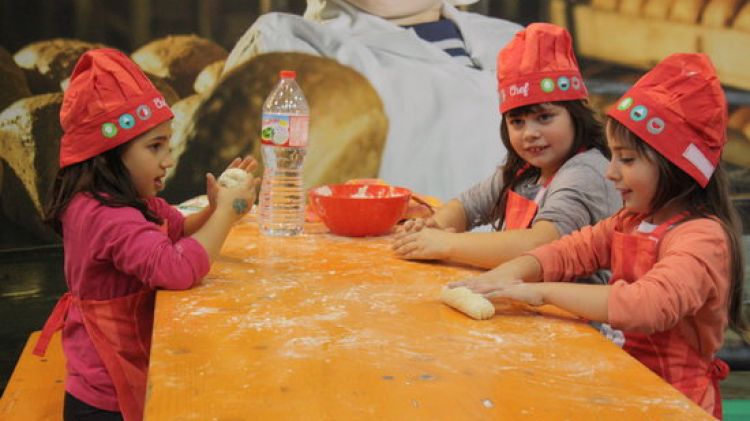 Tres nenes gaudeixen fent pa a la fira 'Jo de gran vull ser...' © ACN