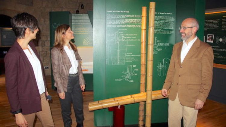 Els responsables de l'exposició al costat del prototipus de la bomba d'aigua de bambú © ACN