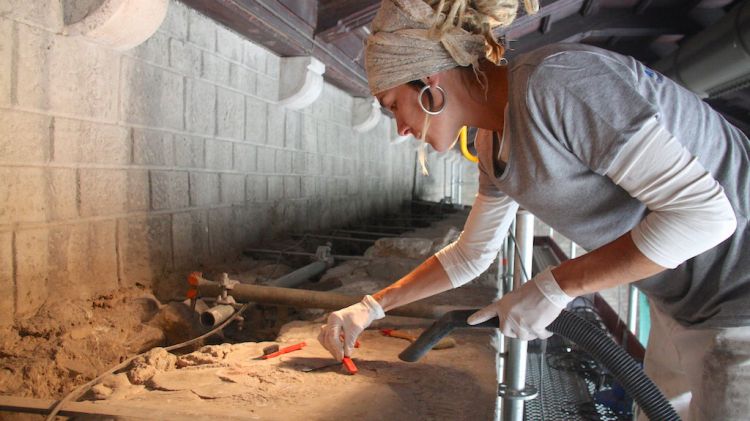 Una restauradora treballant a la part més alta de la portalada de Ripoll © ACN