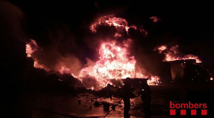 Dos bombers amb les flames que afecten la planta de reciclatge de Sant Feliu de Buixalleu
