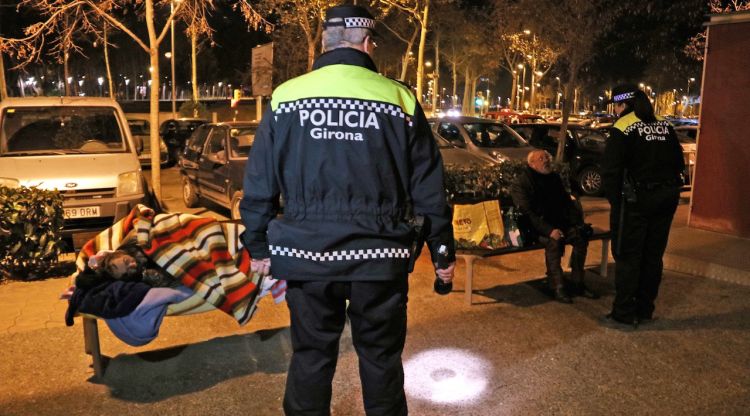 Dos agents s'adrecen a dos indigents per demanar-los que vagin a dormir a La Sopa © ACN