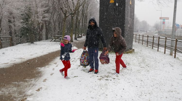 Dos nens i un pare jugant amb la neu a Olot aquesta tarda. ACN