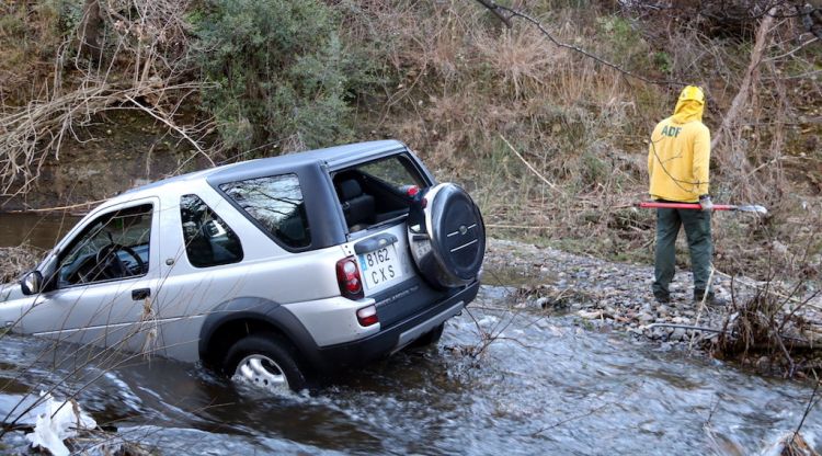 El cotxe embarrancat a la riera d'Anyet amb un ADF al fons treballant a la zona. ACN