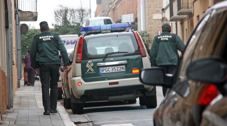 Dos agents de la Guàrdia Civil pujant al vehicle policial durant l'operatiu al carrer Pujades de Figueres. ACN
