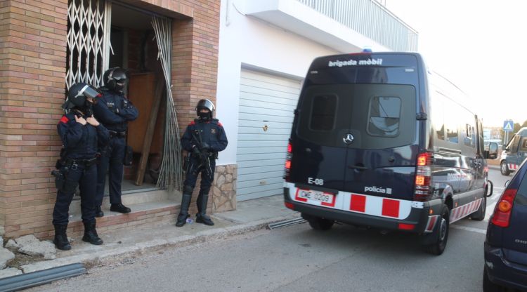 Tres agents dels Mossos d'Esquadra custodien l'entrada d'un dels domicilis. ACN