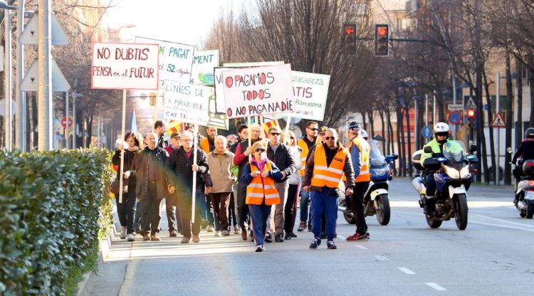 Els manifestants amb les pancartes caminant per un dels carrers de Salt. ACN