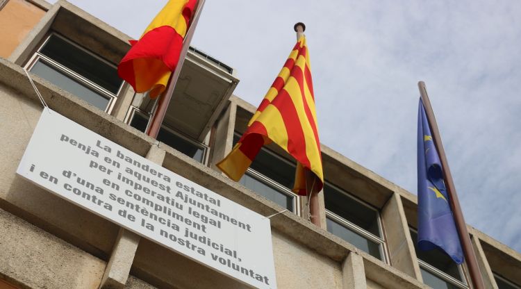 La bandera espanyola onejant amb el cartell de protesta a sota. ACN