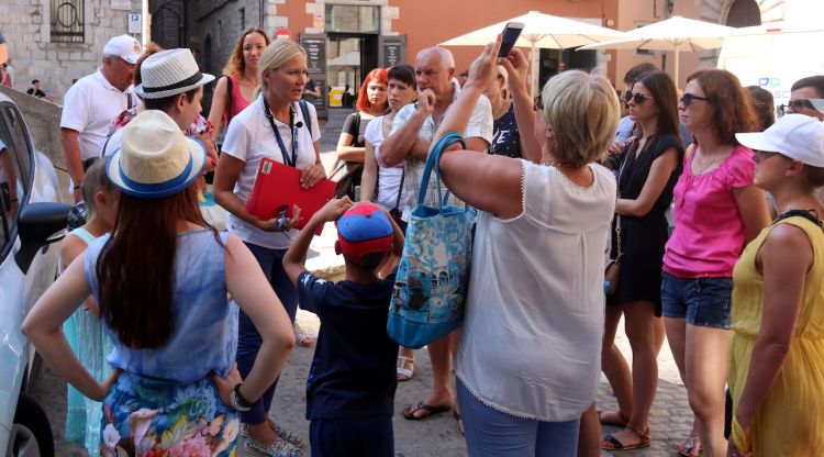 Un grup de turistes amb la seva guia, que porta penjat al coll un micròfon. ACN