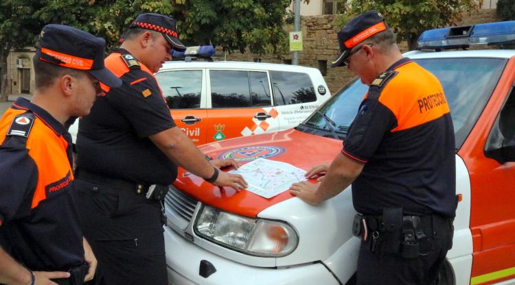 Pla mig de tres voluntaris de Protecció Civil mirant un mapa. ACN